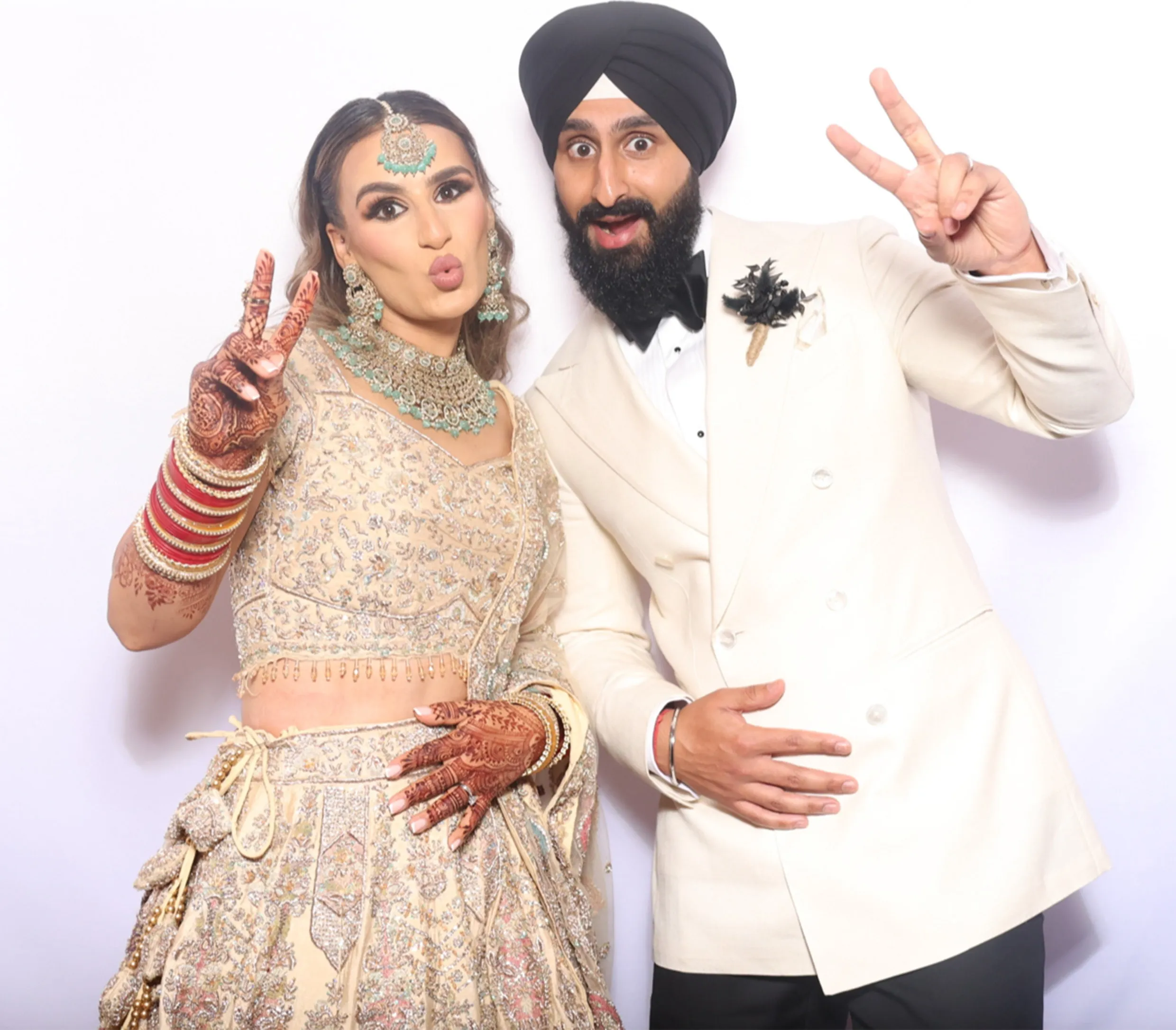 A bride and groom pulling faces and making peace signs in the booth